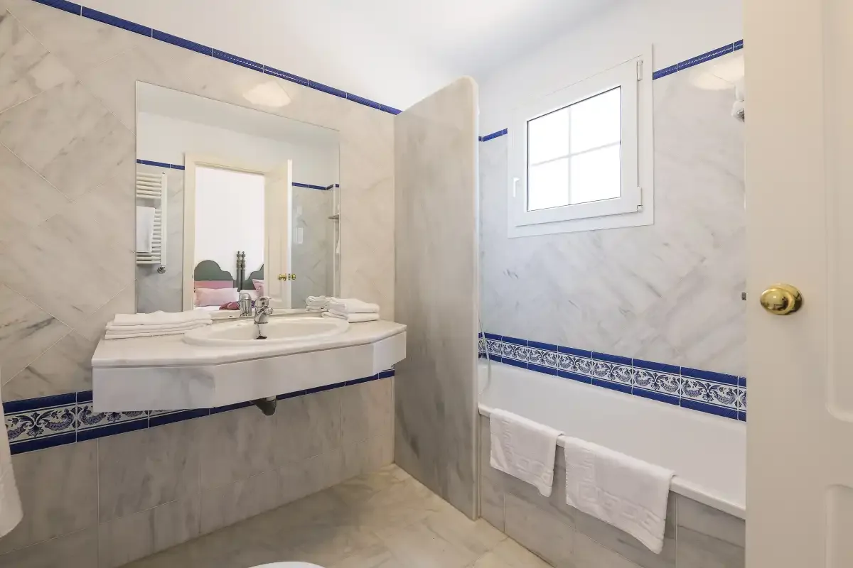 A bathroom with a double sink vanity, a bathtub, and blue decorative tile.