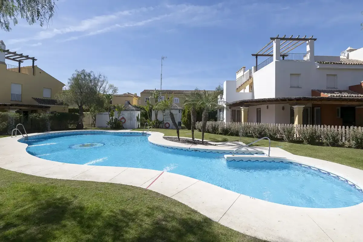 An outdoor swimming pool curves through a landscaped residential courtyard.