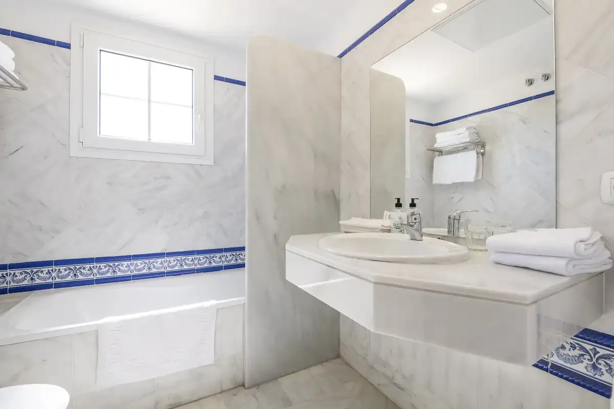 A bathroom with a white bathtub and a sink beneath a large mirror.