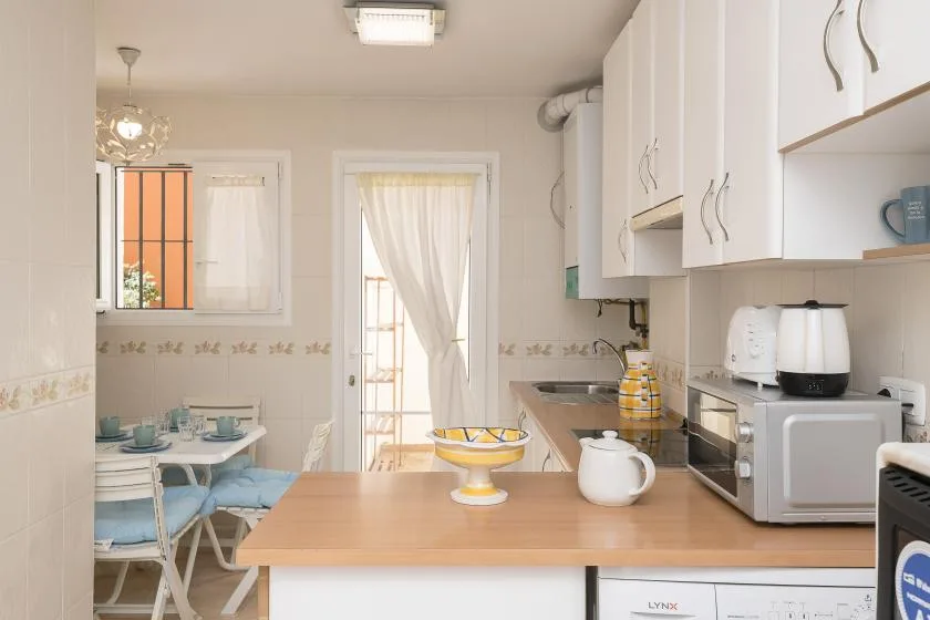 A bright kitchen with a wooden island, white cabinets, and countertop appliances.