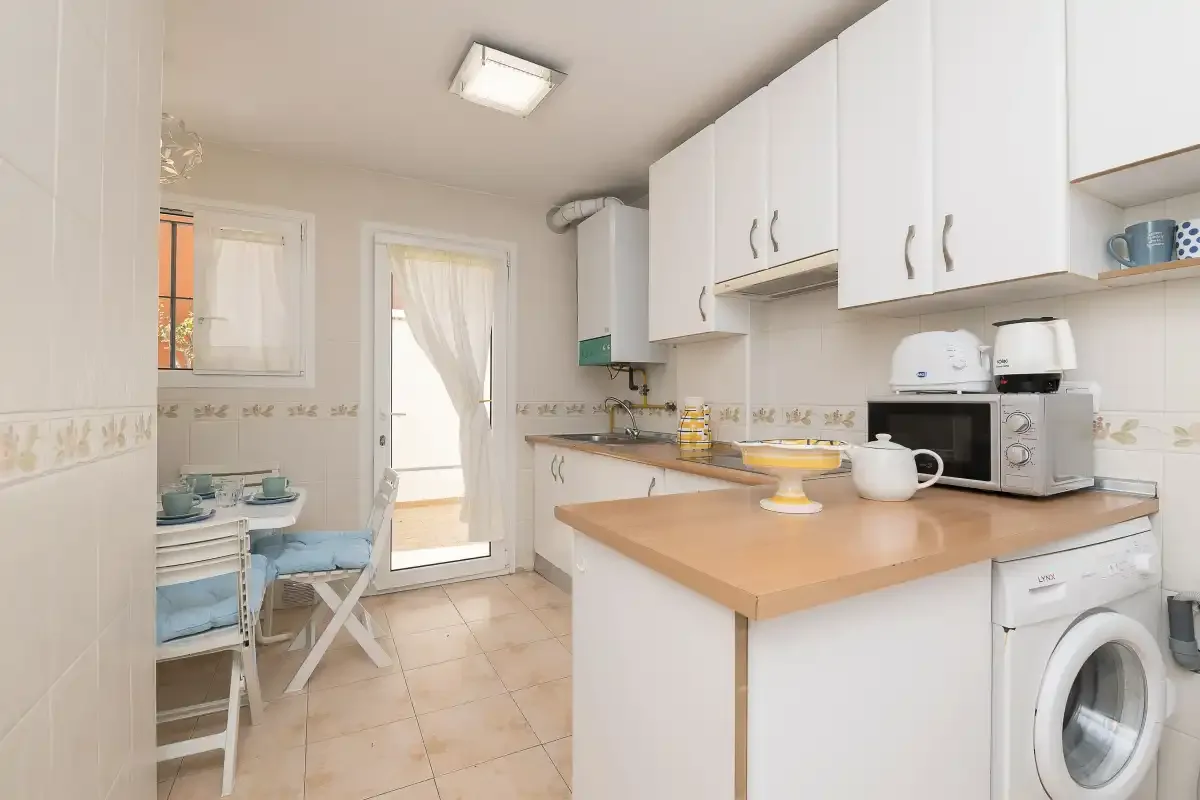 A bright kitchen with white cabinets, a countertop, and a washing machine.