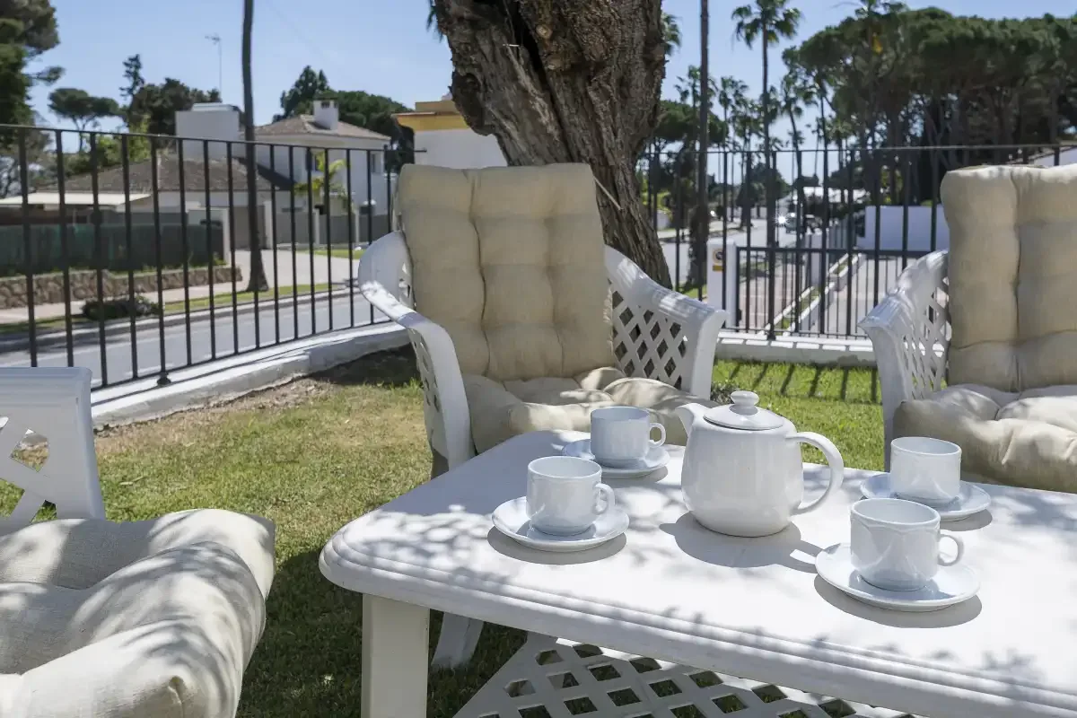 Outdoor seating beside a garden table set with tea cups and a teapot.