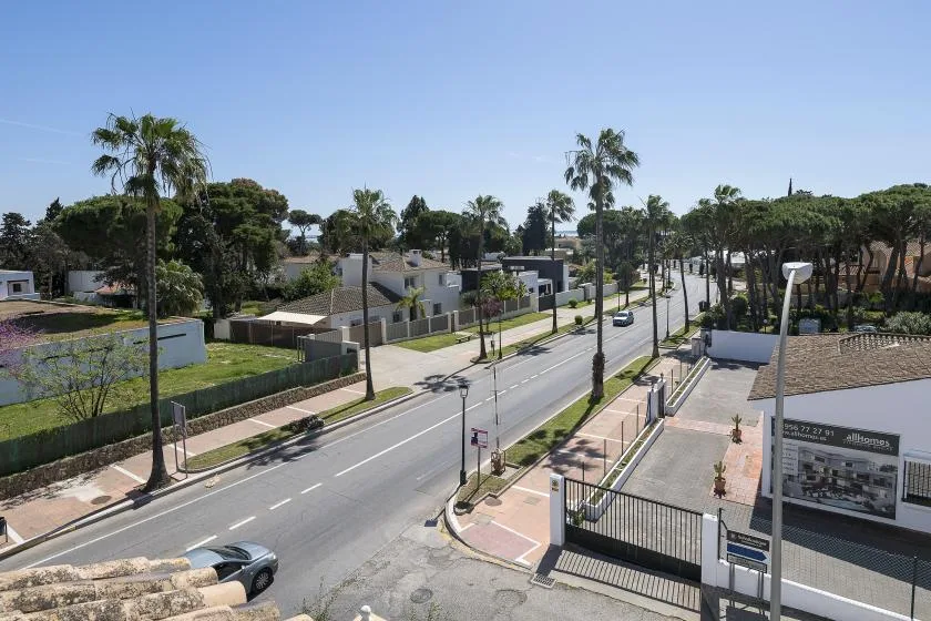 A palm-lined street runs past low buildings and landscaped grounds under a clear sky.