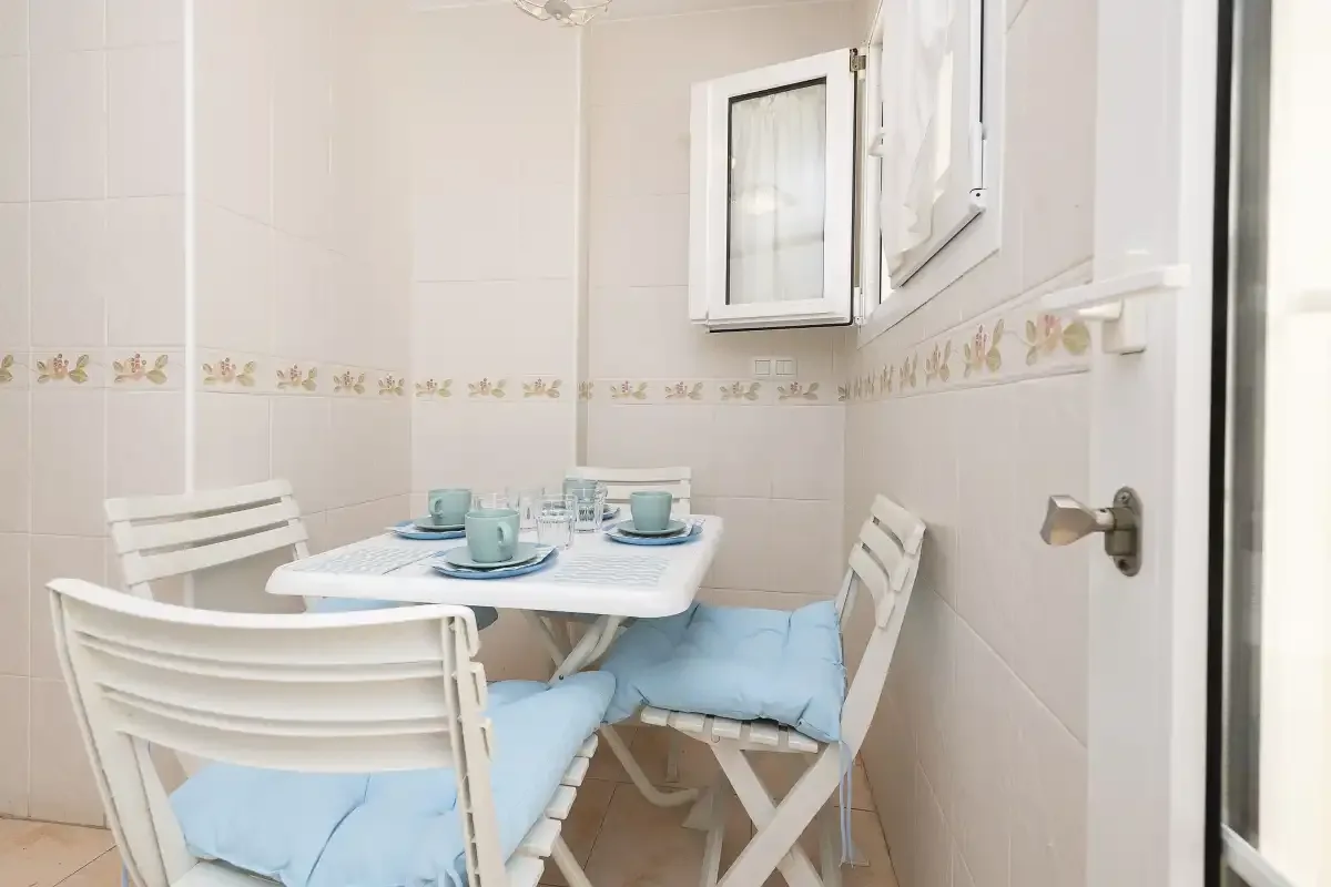 A small dining area with a white table and cushioned seating.