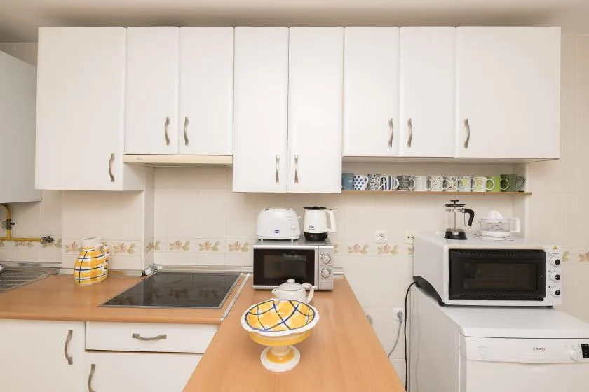 A bright kitchen with white cabinets, a countertop, and several appliances.