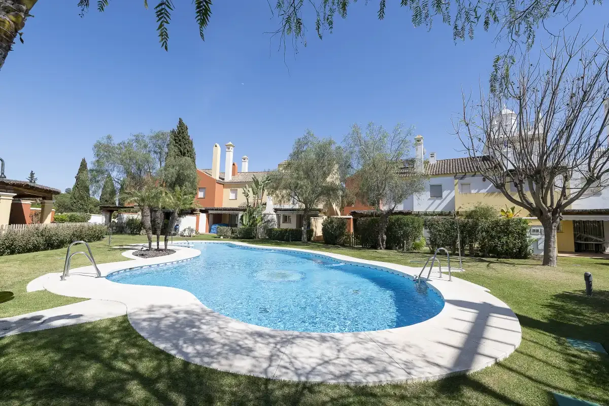 A swimming pool sits in a landscaped courtyard beside residential buildings.