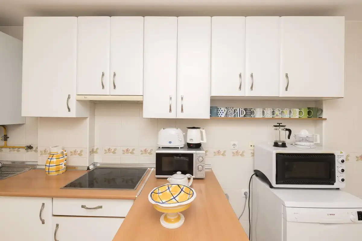 A bright kitchen with white cabinets, a cooktop, and countertop appliances.