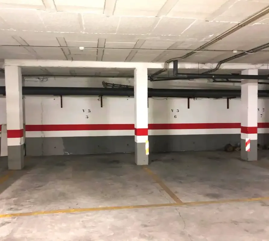 An indoor parking garage with marked spaces and concrete support columns.