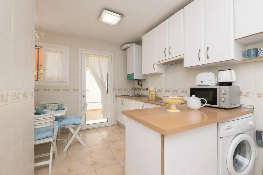 A bright kitchen with white cabinets, a wood-toned counter, and a washing machine.