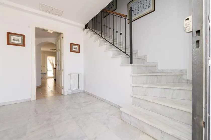 A bright entry hall with a staircase and an open doorway.