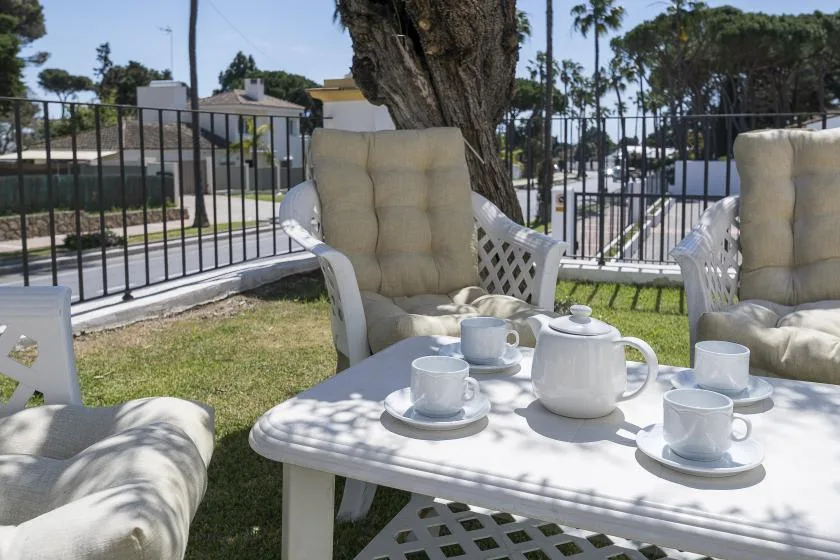 An outdoor seating area with cushioned chairs and a tea set on a table.