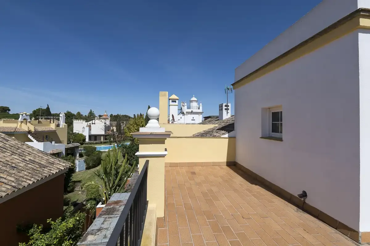 A sunny rooftop terrace overlooks nearby buildings and greenery.