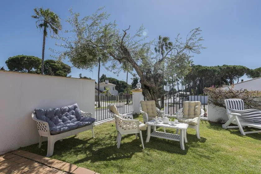 An outdoor seating area with cushioned chairs and a table on a grassy lawn.