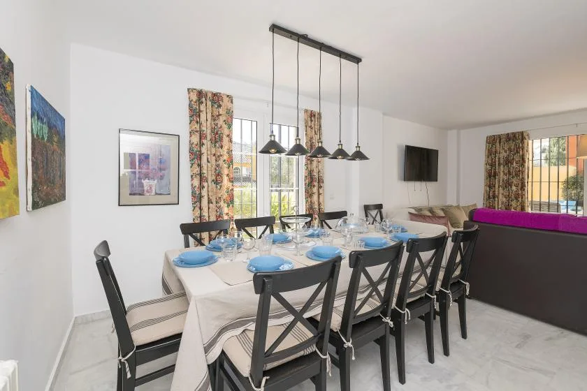 A dining area with a long table set with blue dishes and black chairs.