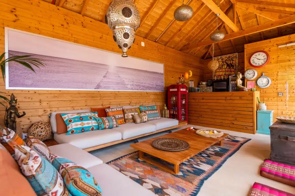 Sunlit indoor lounge with low seating and wooden walls.