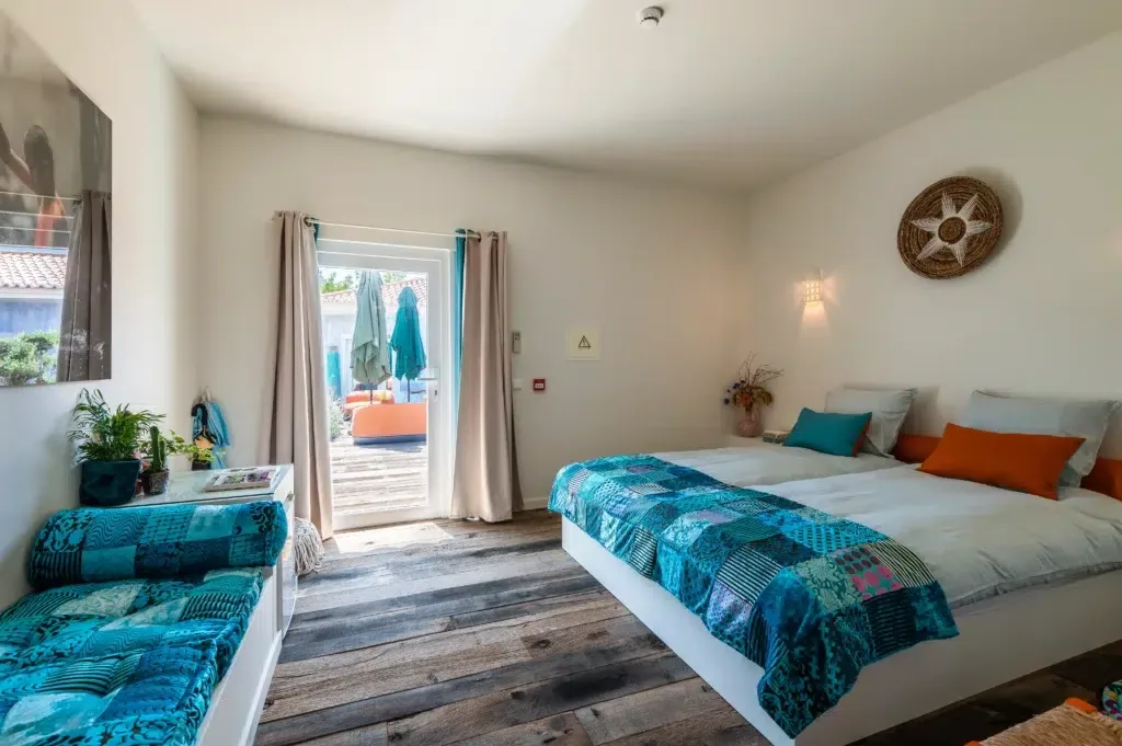 Boutique hotel guest room with a blue patchwork bedspread and patio doors.