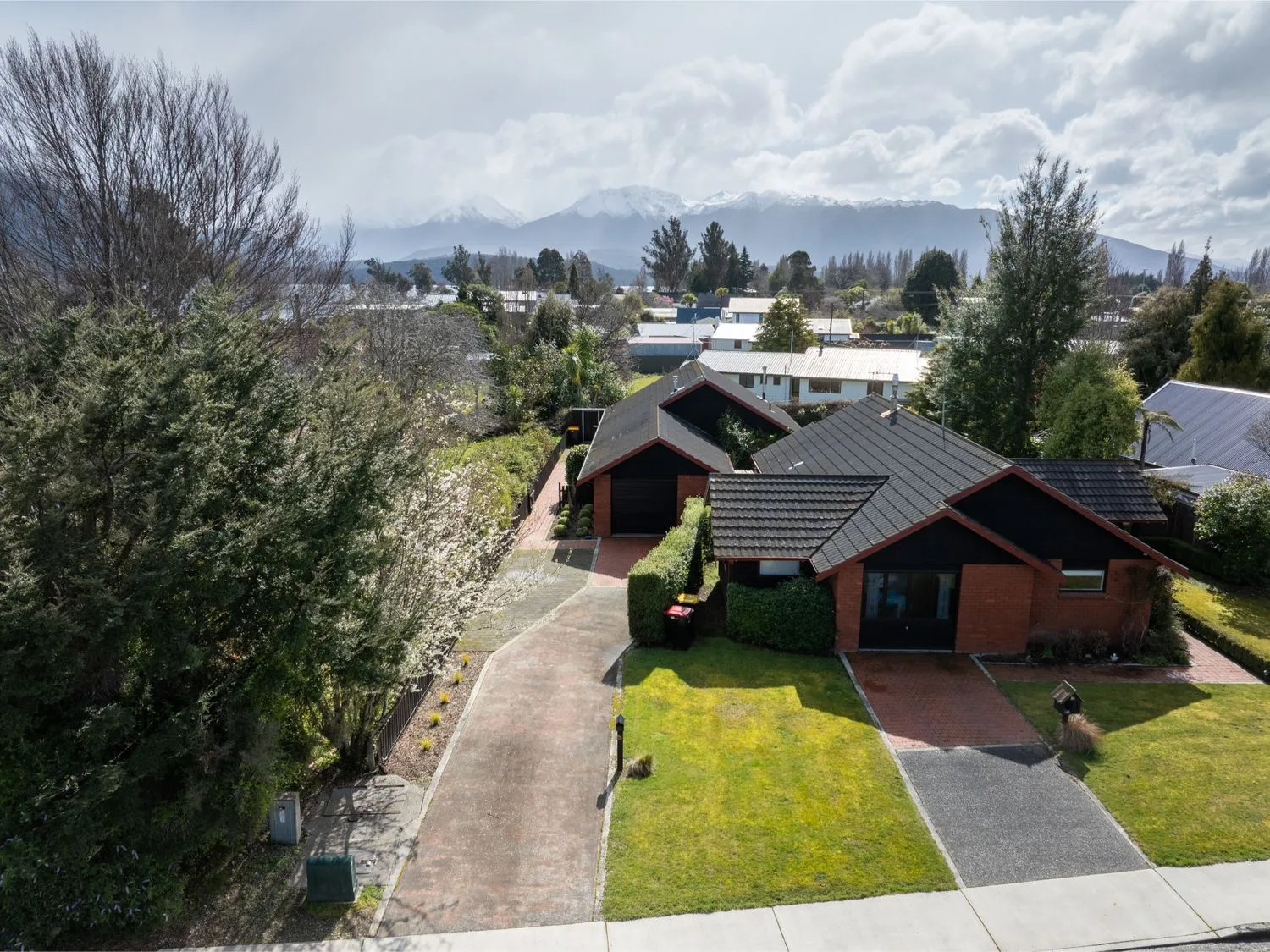 Vista aérea de casas junto a una calle residencial, con montañas a lo lejos.