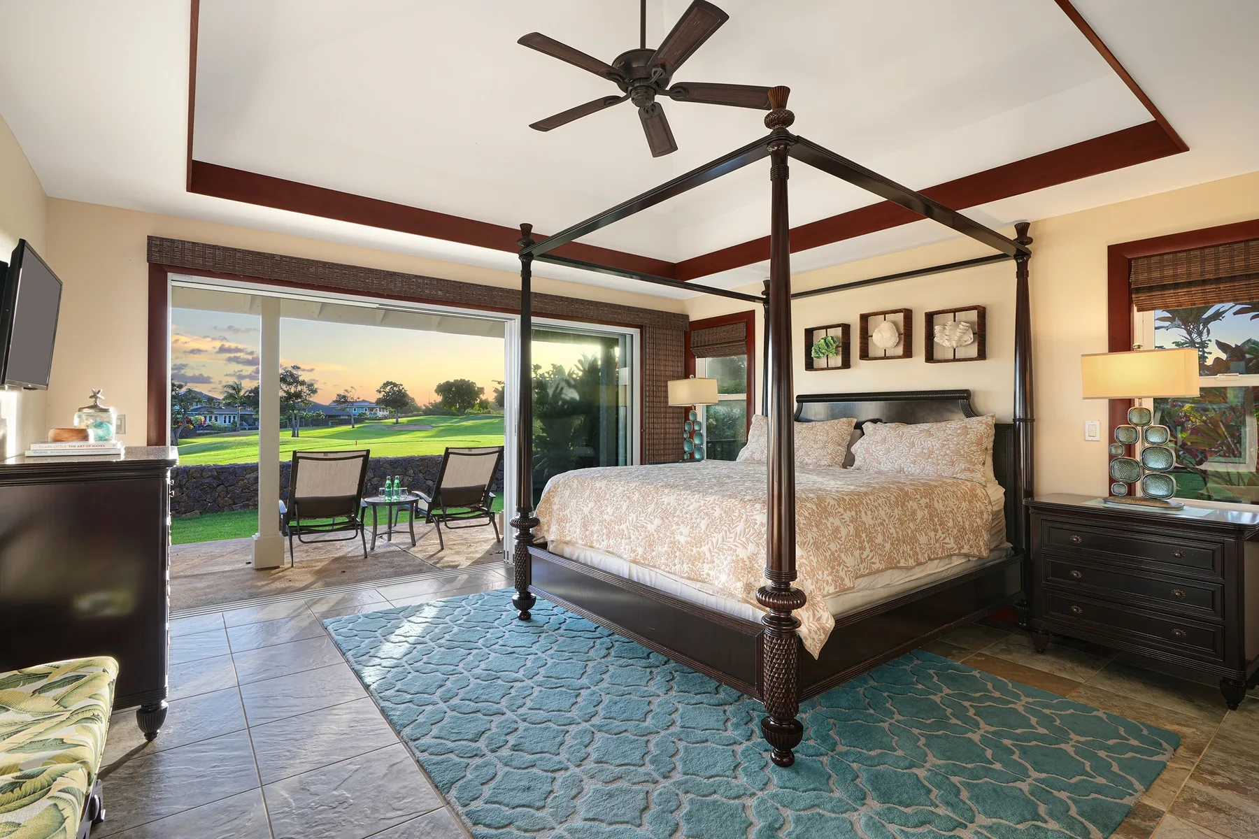 A bedroom with a canopy bed, patterned rug, and sliding glass doors opening to a patio.