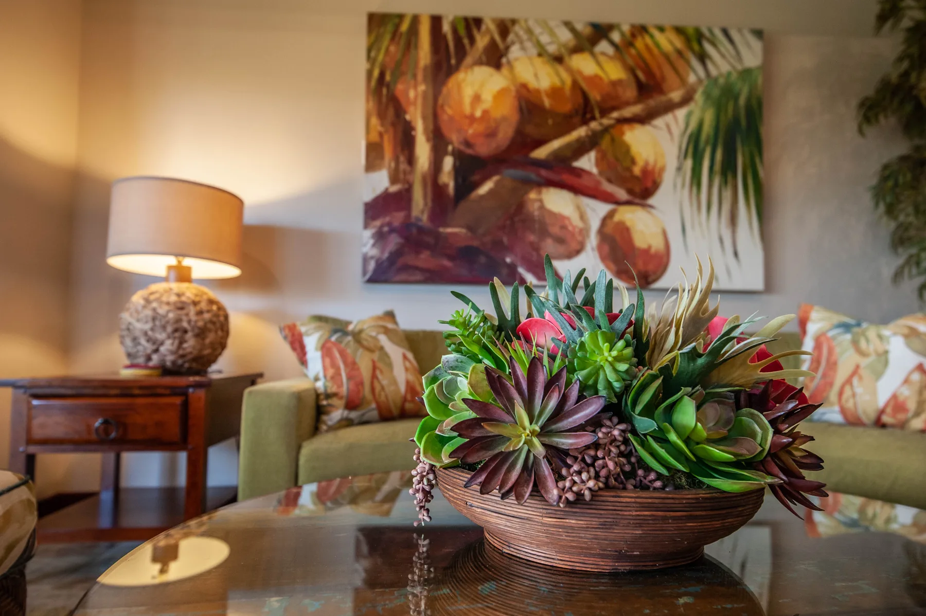 A living room seating area features a colorful succulent arrangement on a glass coffee table.