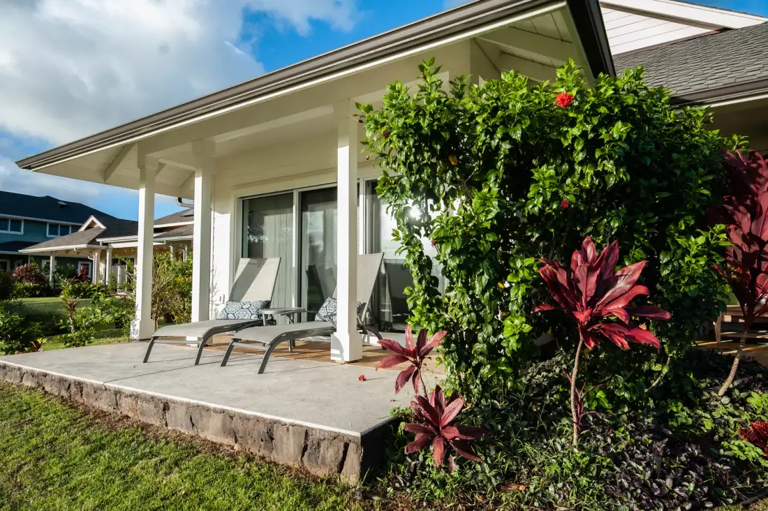 A covered patio with outdoor seating overlooks a landscaped garden.