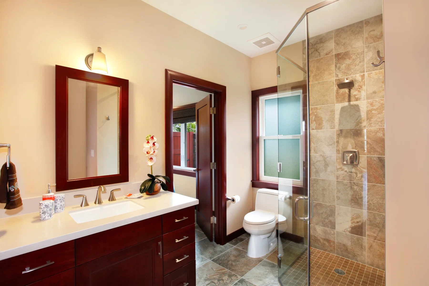 A bathroom with a vanity, toilet, and glass-enclosed shower.