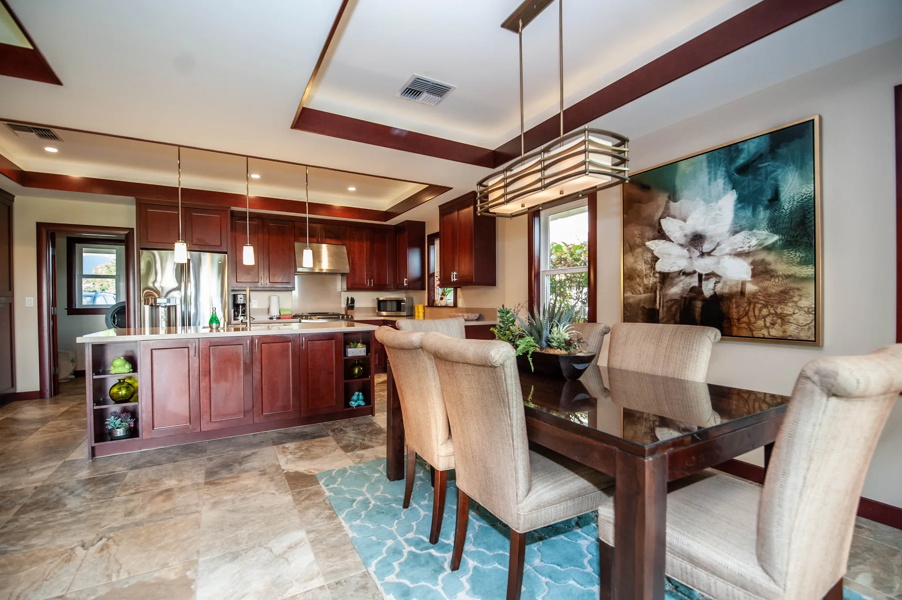An open-plan kitchen and dining area with a dark dining table and upholstered seating.