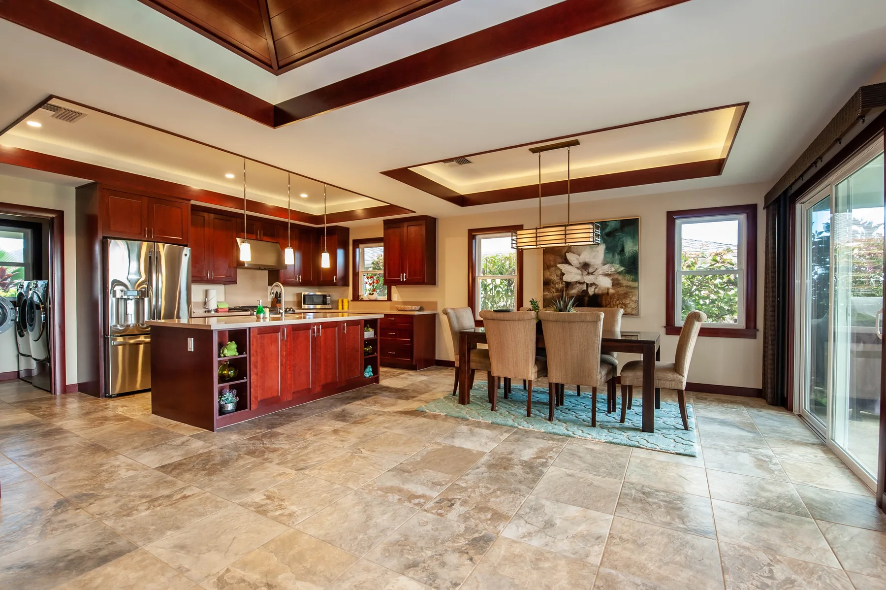 A kitchen and dining area with a central island and a table beside the windows.
