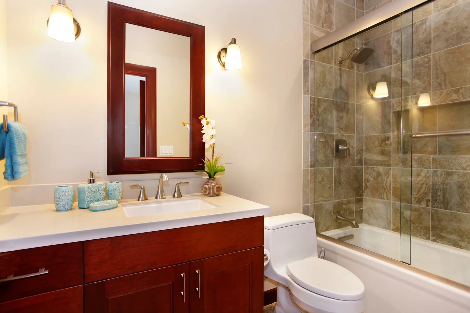 A bathroom vanity with a sink and mirror sits beside a glass shower.