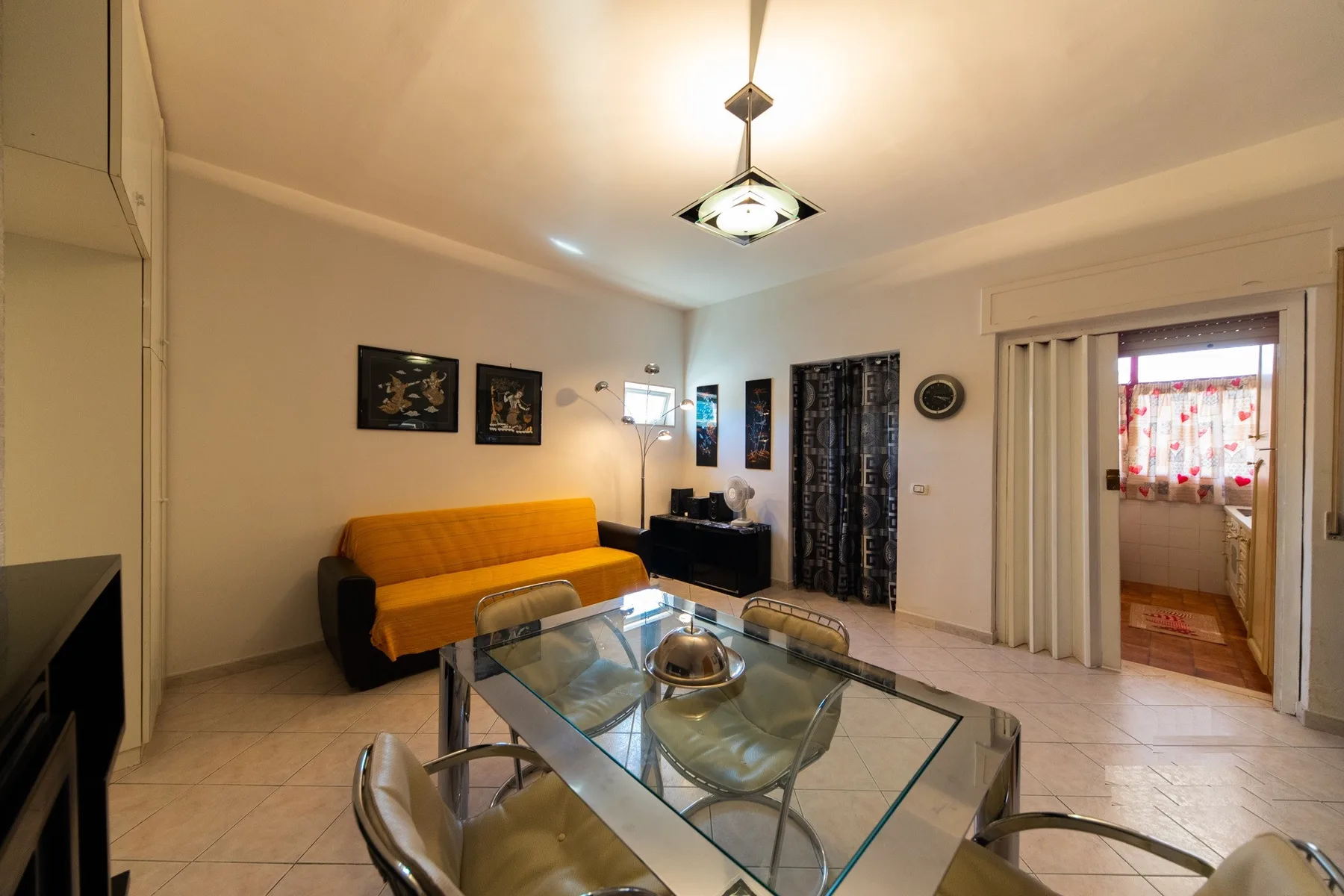 A living and dining area with a glass table and orange-covered seating.