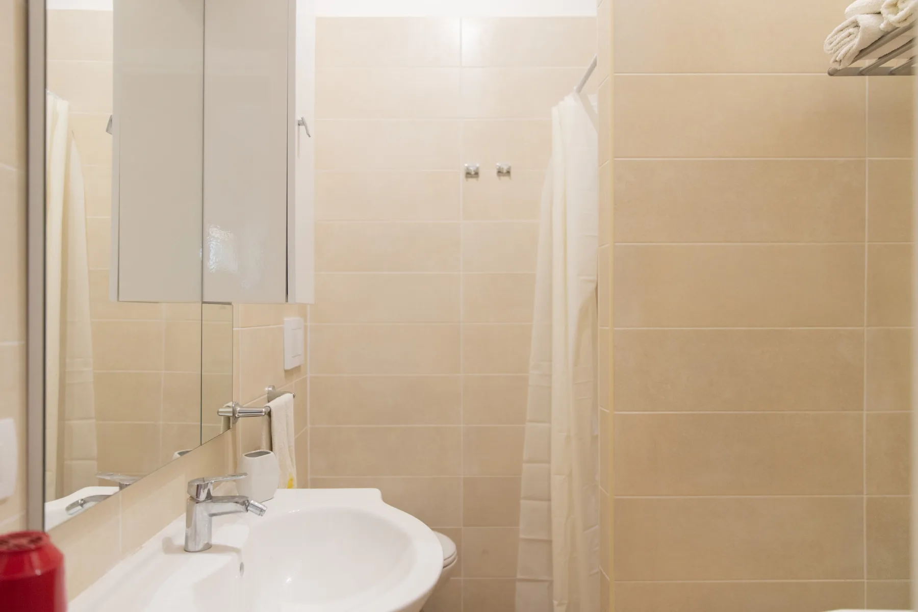 A tiled bathroom with a white sink and a shower curtain.