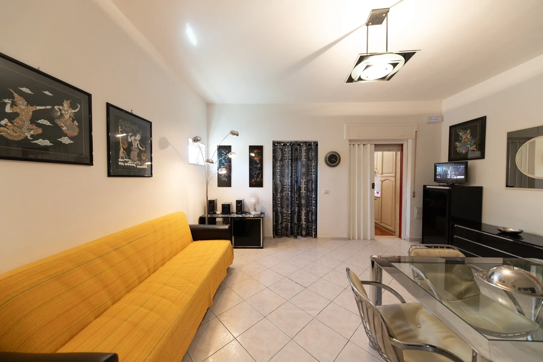 A living and dining area with yellow seating and a glass dining table.