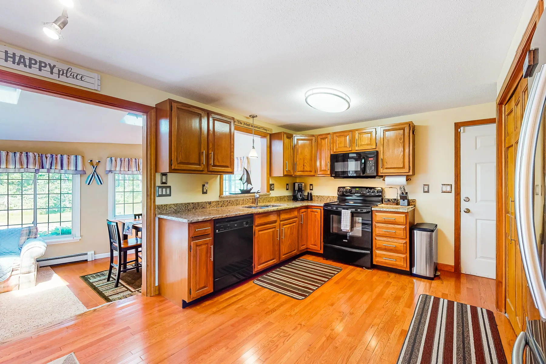 A kitchen with wooden cabinets, appliances, and a breakfast nook by the windows.