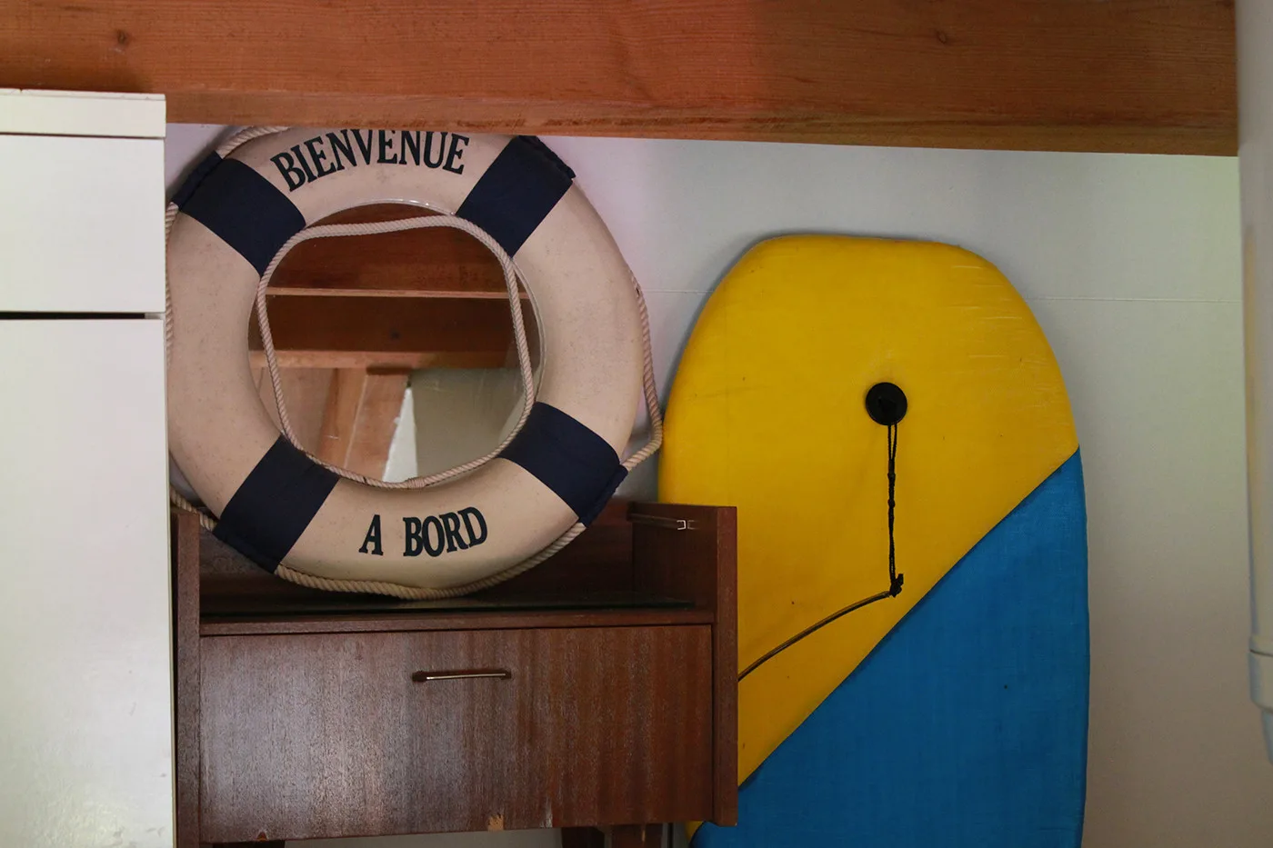 A decorative lifebuoy and colorful surfboard are displayed indoors.