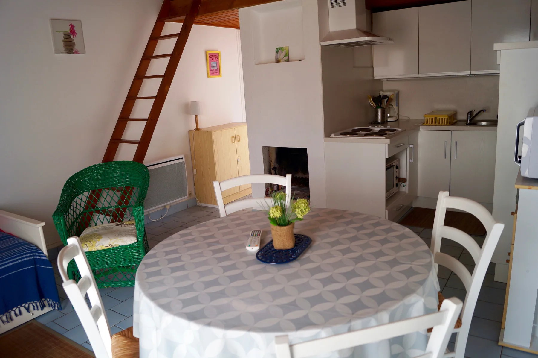 A dining area with a round table and a compact kitchen behind it.