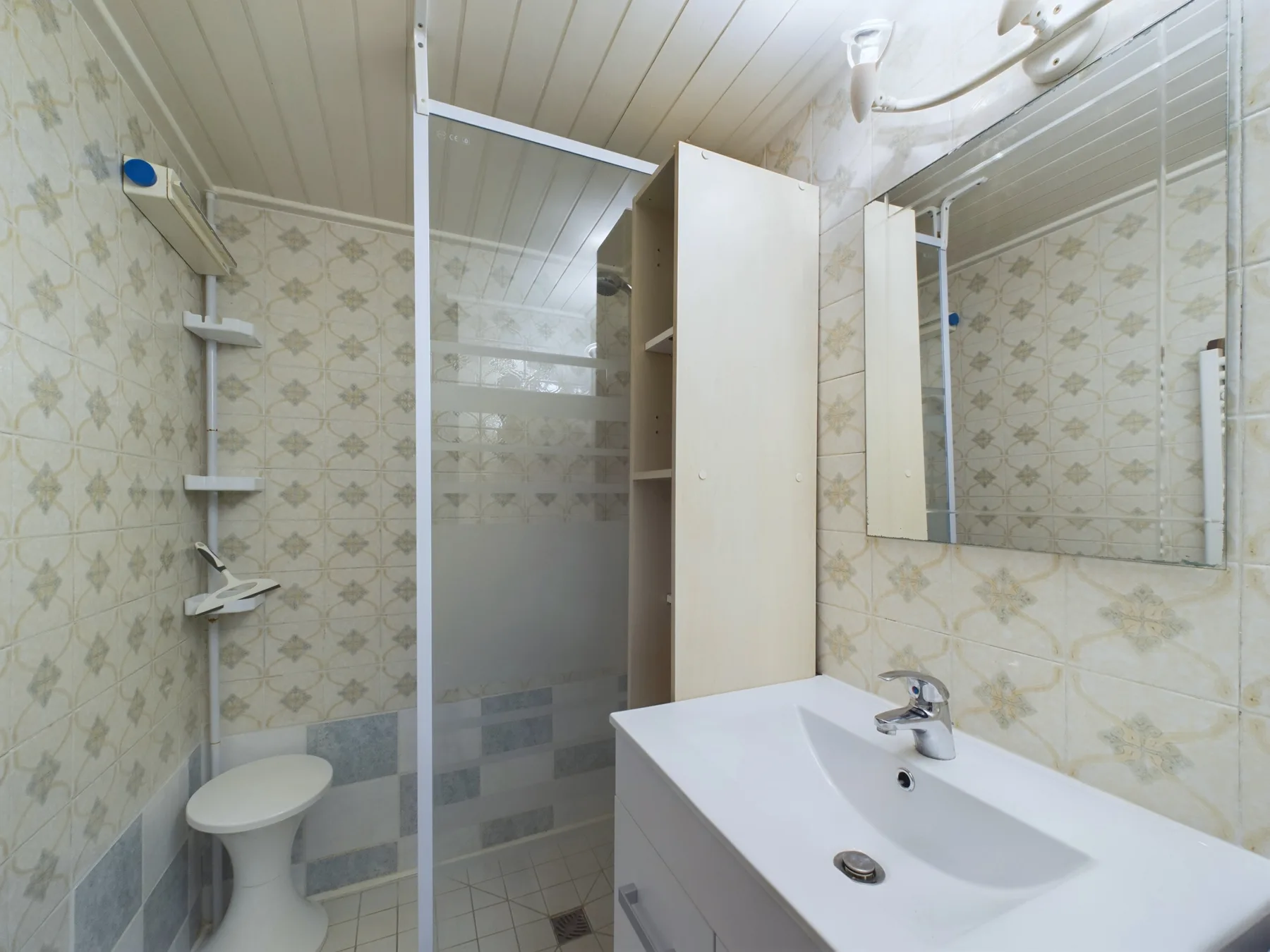 A tiled bathroom with a shower, sink, and mirrored cabinet.