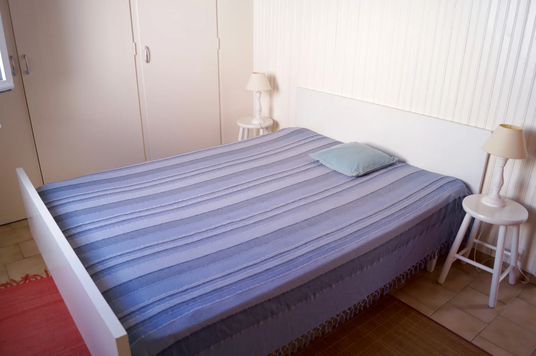 A bedroom with a bed dressed in striped blue bedding.