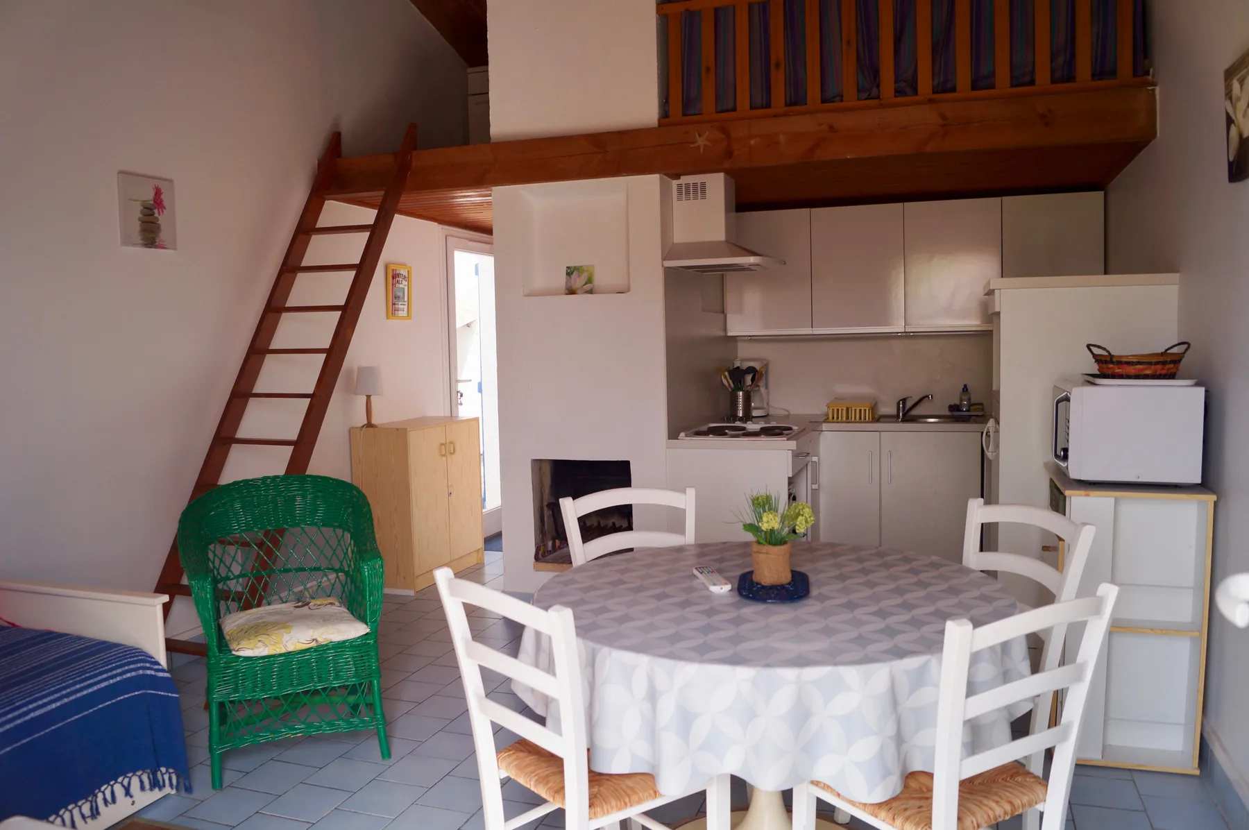 A compact kitchen and dining area sits beneath a wooden loft.