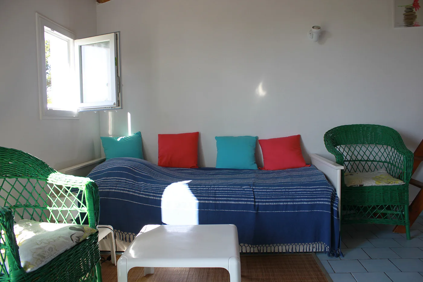 A living room with blue seating, colorful cushions, and green chairs.