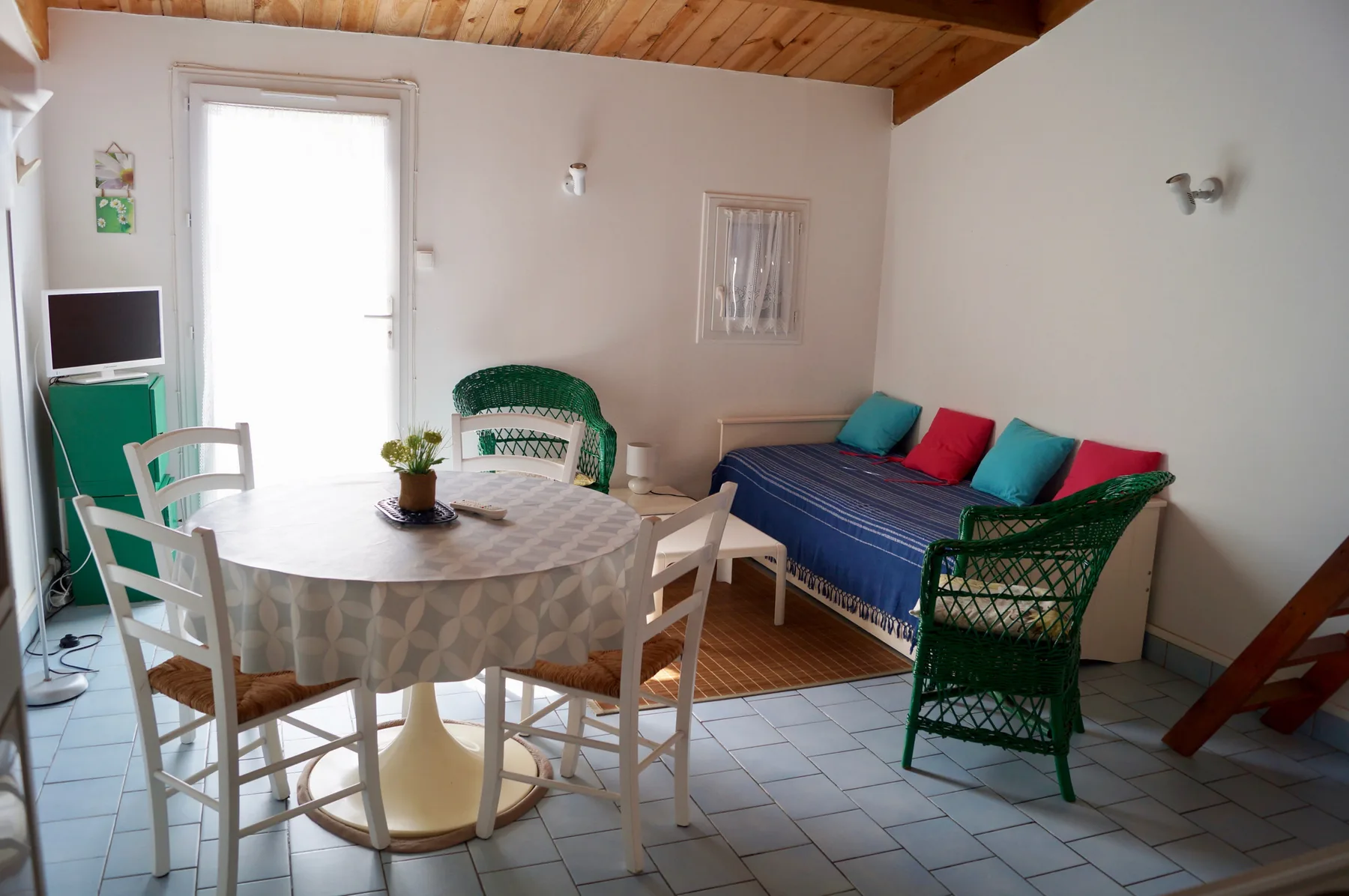 A dining and sitting area with a round table, chairs, and a blue daybed.