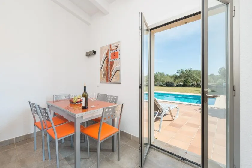 Un comedor luminoso da a un patio con piscina.