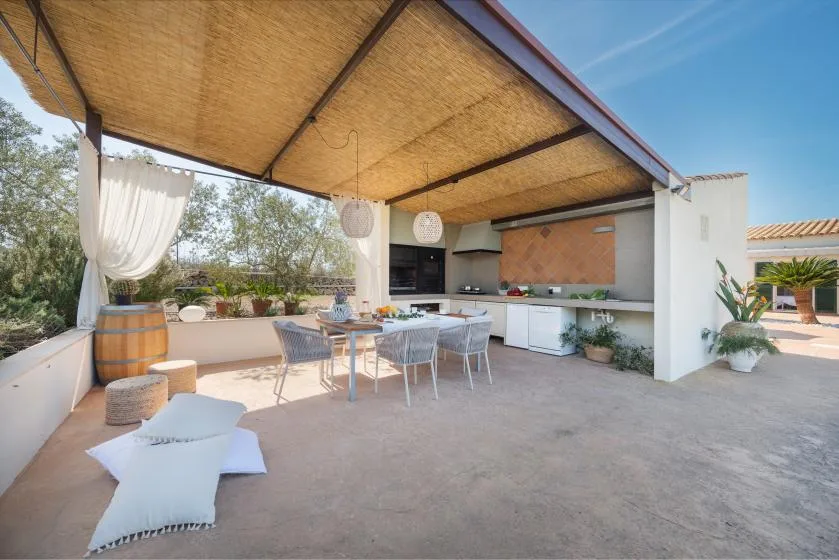 Comedor exterior cubierto con una mesa junto a una cocina integrada.
