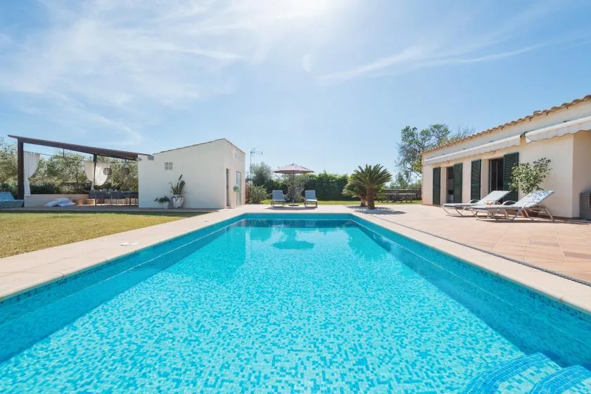 Una piscina al aire libre está junto a un patio y edificios bajos.
