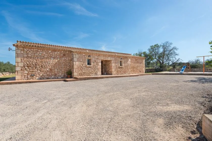 Un edificio de piedra da a un patio abierto de grava bajo un cielo despejado.