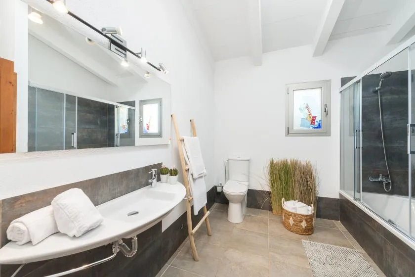 Un baño luminoso con un lavabo curvo, un inodoro y una ducha de vidrio.