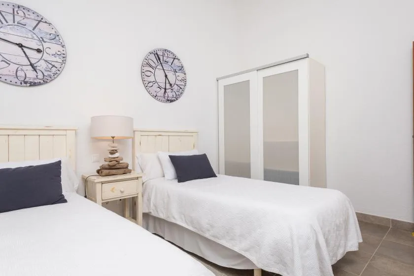 Un dormitorio con dos camas individuales, una mesita de noche y relojes de pared.