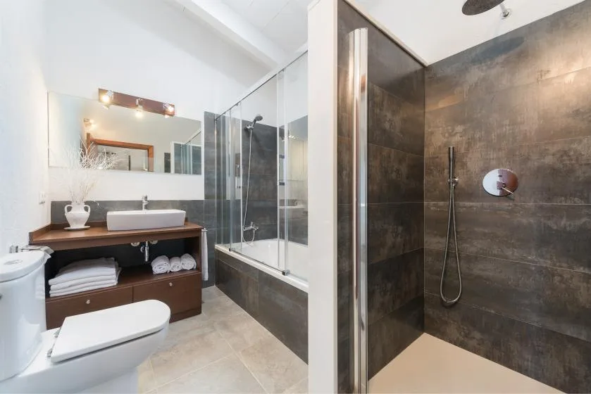 Un baño moderno con tocador, lavabo, inodoro y ducha de vidrio.