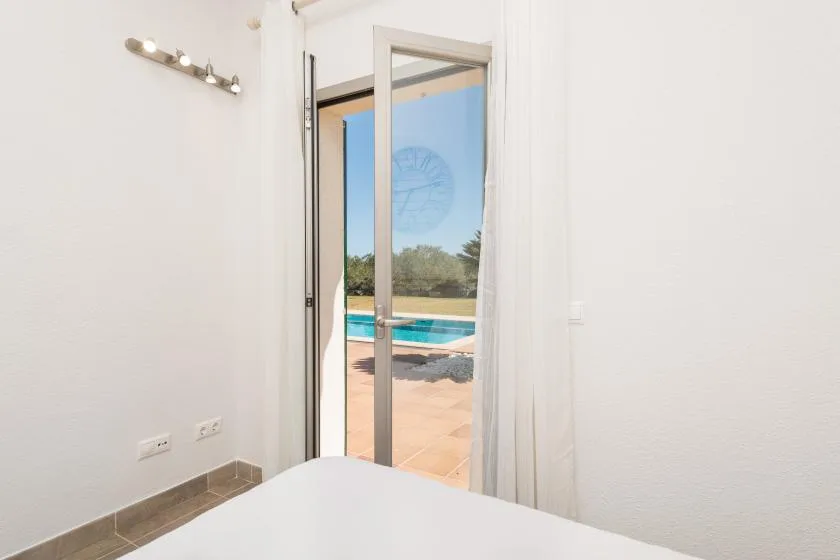 Un dormitorio luminoso se abre a un patio y una piscina a través de una puerta de vidrio.