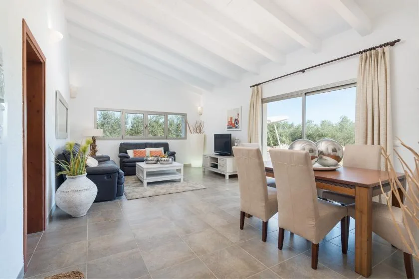 Una luminosa sala de estar y comedor de planta abierta, con grandes ventanas y muebles neutros.