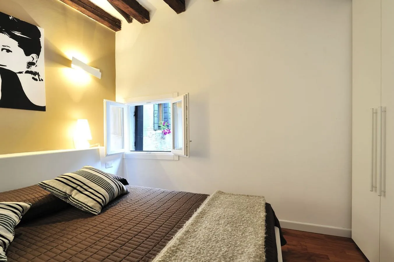 A bedroom with a bed beside an open window.