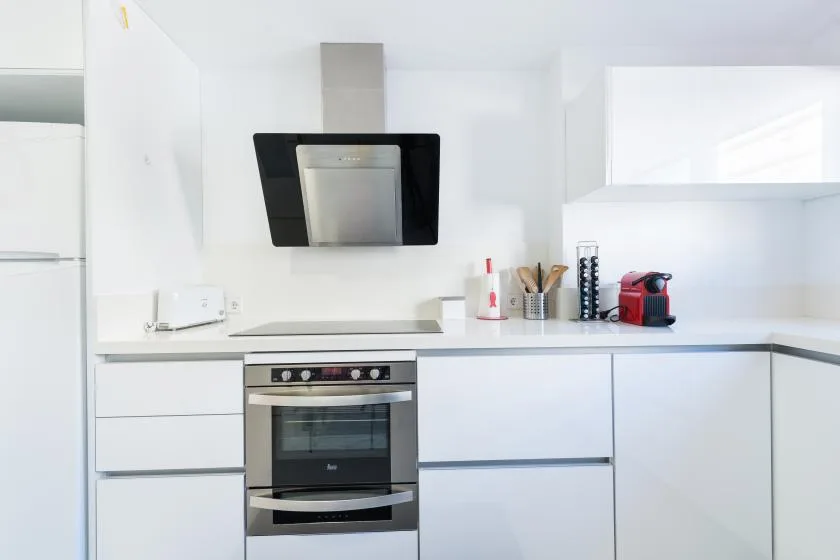 Una cocina moderna y luminosa con armarios blancos y horno empotrado.
